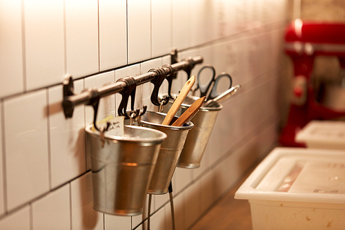 food, cooking and baking concept - bakery kitchen tools hanging on wall in buckets