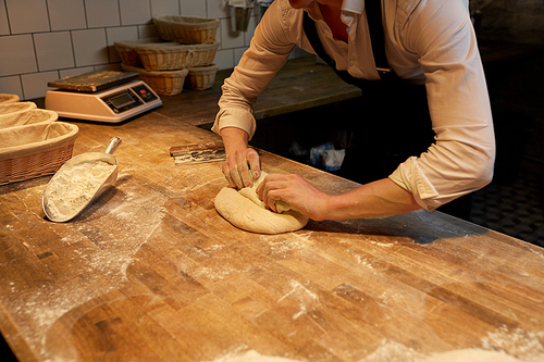 food cooking, baking and people concept - chef or baker making dough at bakery
