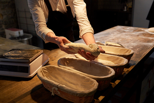 food cooking, baking and people concept - chef or baker putting yeast bread dough into baskets for rising at bakery kitchen