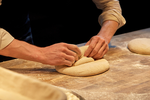 food cooking, baking and people concept - chef or baker making dough at bakery