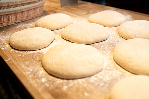 food, cooking and baking concept - yeast bread dough rising on wooden kitchen table at bakery