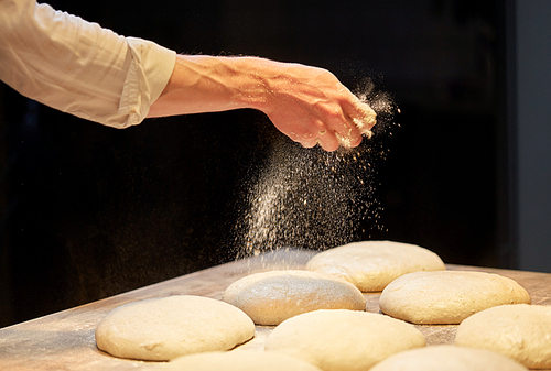 food cooking, baking and people concept - chef or baker making bread and pouring flour to dough at bakery