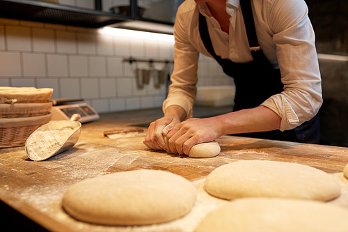 food cooking, baking and people concept - baker making bread dough at bakery kitchen