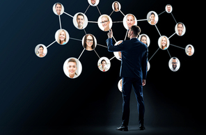 business, people and technology concept - businessman in suit with virtual icons of corporate network over black background