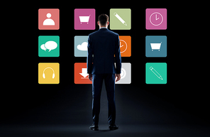 business, people and technology concept - businessman in suit looking at virtual menu icons over black background