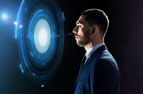 business, people and technology concept - businessman in suit looking at virtual projection over black background