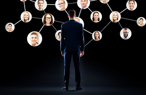 business, people and technology concept - businessman in suit with virtual icons of corporate network over black background