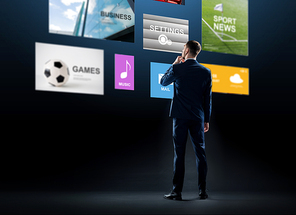 business, people and technology concept - businessman in suit looking at virtual applications over black background