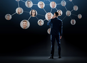 business, people and technology concept - businessman in suit with virtual icons of corporate network over black background