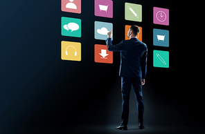 business, people and technology concept - businessman in suit touching virtual menu icons over black background