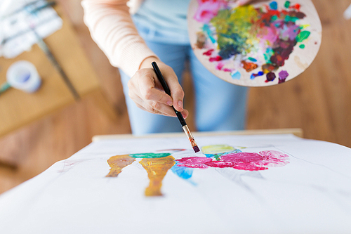 art, creativity and people concept - close up of artist with palette and paint brush painting still life on paper at studio