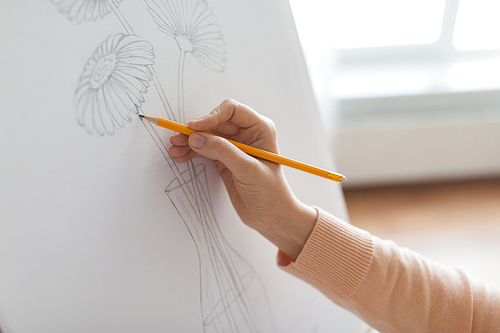 art, creativity and people concept - artist hands with graphite pencil drawing still life picture of flower in vase on paper at studio