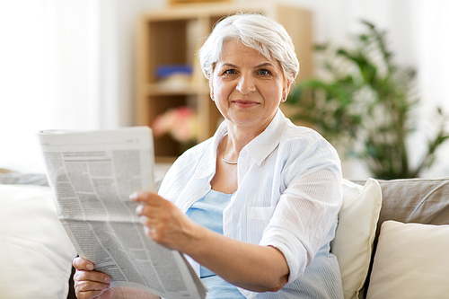 age and people concept - senior woman reading newspaper at home