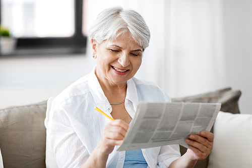 age and people concept - senior woman marking newspaper ad at home