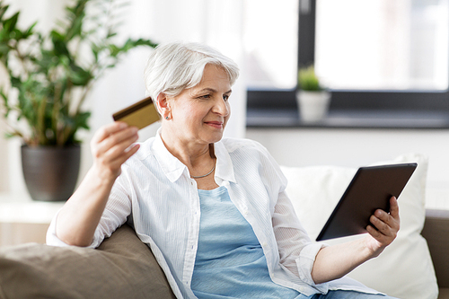 technology, online shopping, age and people concept - senior woman with tablet pc computer and credit or bank card at home