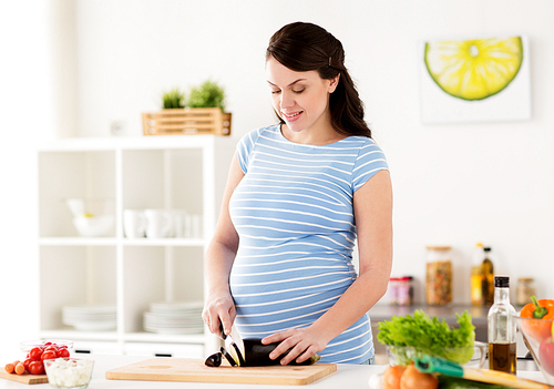 healthy eating, pregnancy and people concept - pregnant woman cooking and chopping vegetable at home kitchen