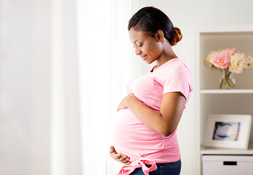 pregnancy, people and expectation concept - happy pregnant african american woman with big belly at home