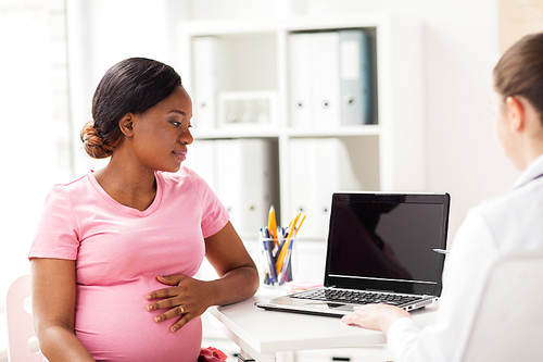 pregnancy, medicine, healthcare and people concept - gynecologist doctor with laptop computer and pregnant african american woman meeting at hospital