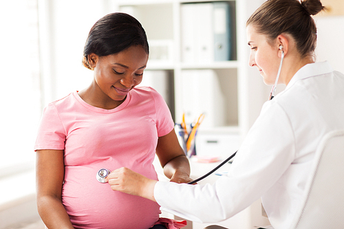 pregnancy, medicine, healthcare and people concept - gynecologist doctor with stethoscope listening to pregnant african american woman baby heartbeat at hospital