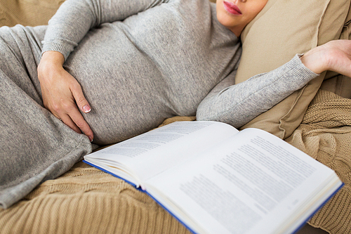 pregnancy, people and motherhood concept - close up of pregnant woman with book sleeping at home