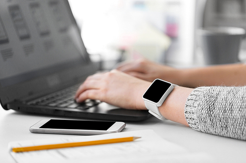 app design, technology and business concept - designer with smart watch and laptop at office