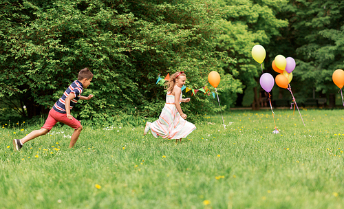 friendship, childhood, leisure and people concept - happy kids or friends playing tag game at birthday party in summer park