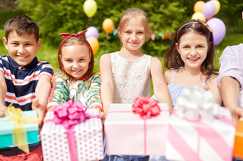 holidays, childhood and celebration concept - happy kids with gifts on birthday party at summer park