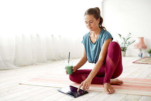 fitness, technology and healthy lifestyle concept - woman with tablet pc computer and cup of smoothie at yoga studio