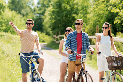 people, leisure and lifestyle concept - happy young friends riding fixed gear bicycles in summer