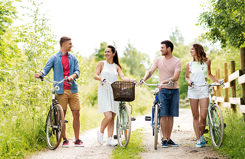 people, leisure and lifestyle concept - happy young friends with fixed gear bicycles on country road in summer