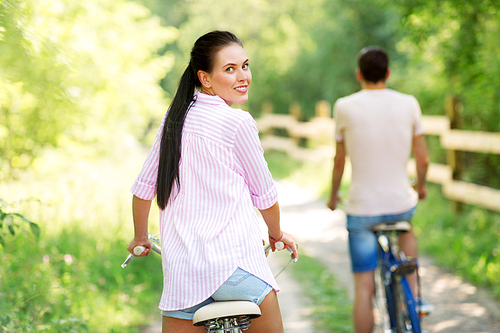 people, leisure and lifestyle concept - happy young couple with bicycles at summer park