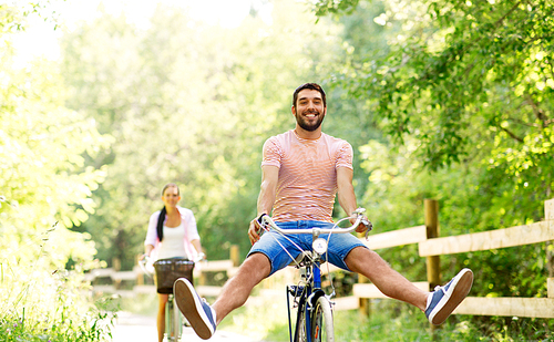 cycling, leisure and lifestyle concept - happy young couple with bicycles at summer park