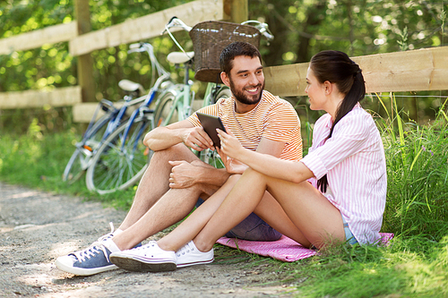 people, technology and lifestyle concept - happy couple with tablet pc computer and bicycles at summer park