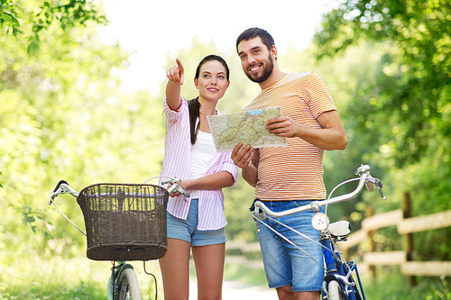 travel, trip, leisure and lifestyle concept - happy young couple with map and bicycles looking for location at country in summer