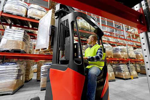 logistic business, shipment and loading concept - loader operating forklift at warehouse
