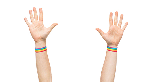 lgbt, same-sex relationships and homosexual concept - close up of male hands wearing gay pride awareness wristbands