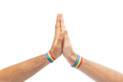 lgbt, same-sex love and homosexual relationships concept - close up of male couple hands with gay pride rainbow awareness wristbands making high five gesture
