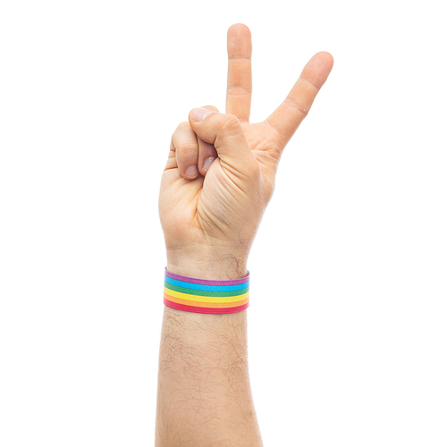 lgbt, same-sex relationships and homosexual concept - close up of male hand wearing gay pride awareness wristband showing peace sign