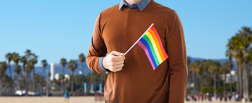 gay pride, lgbt and homosexual concept - close up of man with rainbow flag over venice beach background in california