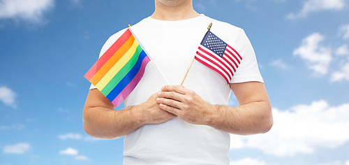 lgbt, same-sex relationships and homosexual concept - close up of man holding gay pride rainbow and american flag over blue sky and clouds background