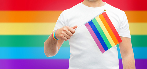 lgbt, same-sex relationships and homosexual concept - close up of man wearing gay pride awareness wristband holding rainbow flag