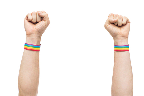 lgbt, same-sex relationships and homosexual concept - close up of male hands wearing gay pride awareness wristbands showing fist