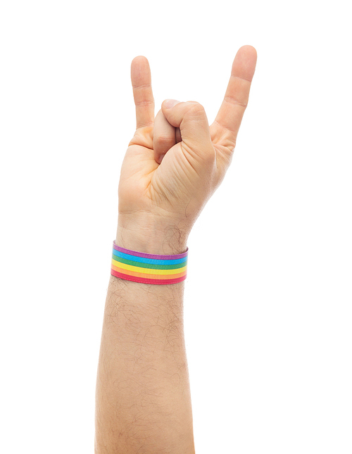 lgbt, same-sex relationships and homosexual concept - close up of male hand wearing gay pride awareness wristband showing rock or hand-horns sign