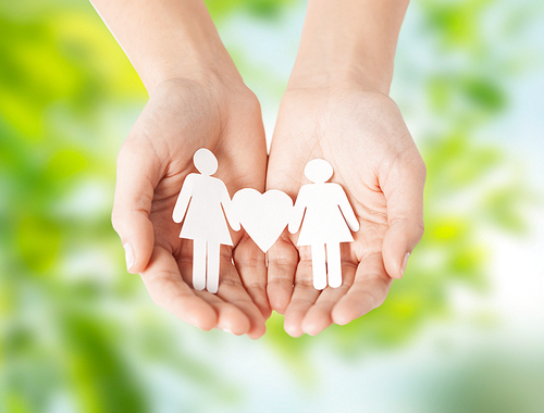 lgbt and gay concept - hands holding paper female couple pictogram with heart over green natural background