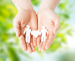 lgbt and gay concept - hands holding paper male couple pictogram with heart over green natural background