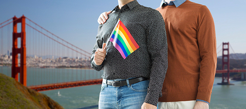 gay pride, lgbt and homosexual concept - close up of happy male couple with rainbow flags over golden gate bridge in san francisco bay background