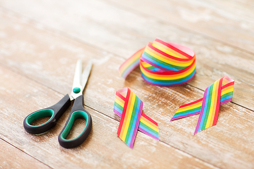 homosexual and lgbt concept - gay awareness ribbon and scissors on wooden boards