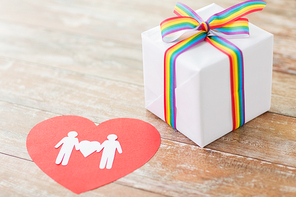 homosexual and lgbt concept - close up of gift box with gay pride awareness ribbon and male couple pictogram on red paper heart on wooden boards