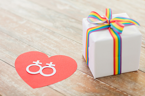 homosexual and lgbt concept - close up of gift box with gay pride awareness ribbon and female gender symbol on red heart on wooden boards