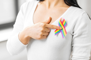 homosexual and lgbt concept - close up of woman showing gay pride awareness ribbon on her chest